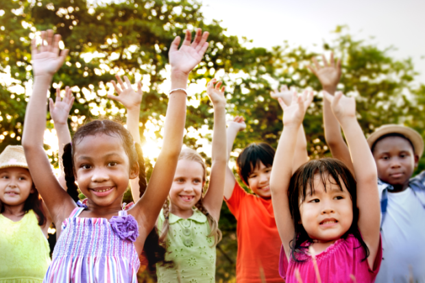 Photo of multiple kids holding their hands up in the air