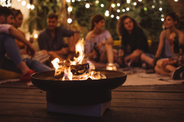 Photo of multiple teens sitting around a fire pit