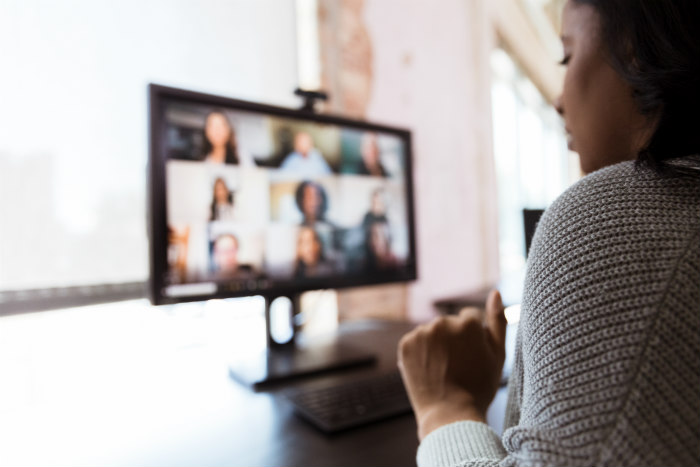 Black woman looking at a Zoom sceen of other people 