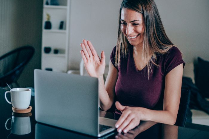 Woman waving at a laptop screen