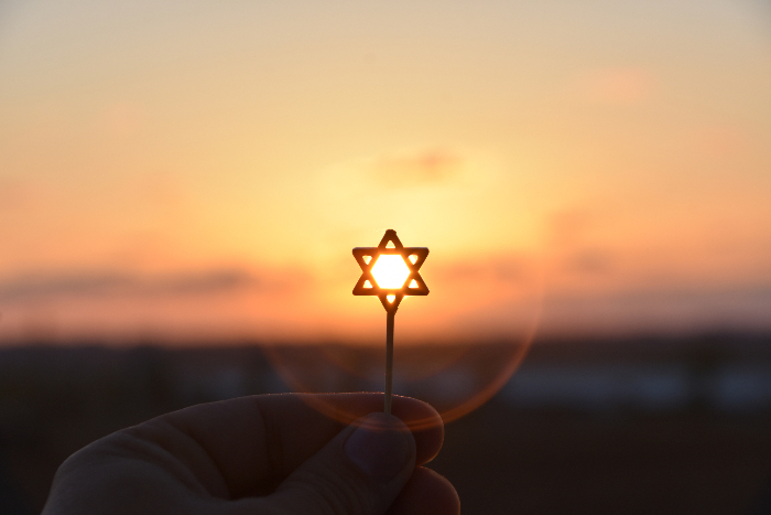 Small Star of David held up against a sunset