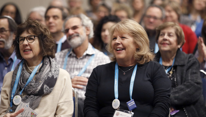 A group of people smiling and clapping in an audience at the URJ Biennial