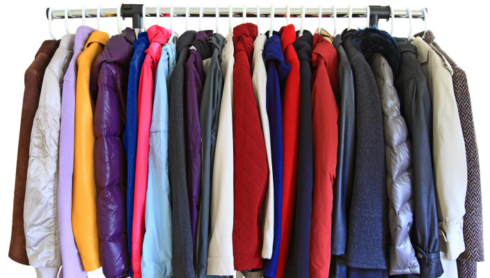 Assorted coats hanging on hangers on a coat rack