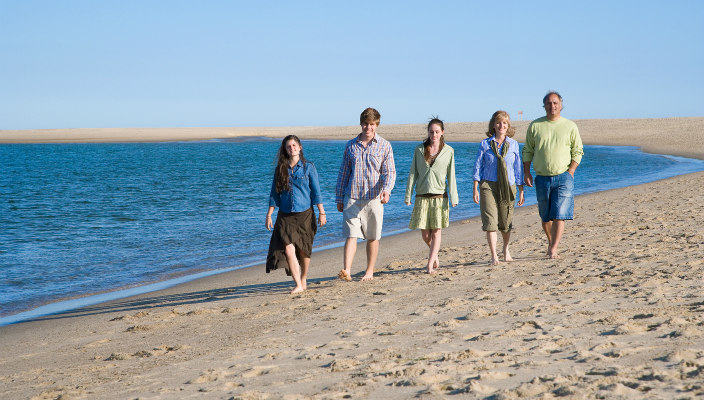 Family (mother, father, and three teens) walking on the beach