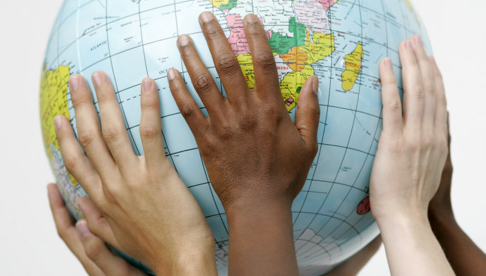Hands of people of different races holding up a globe
