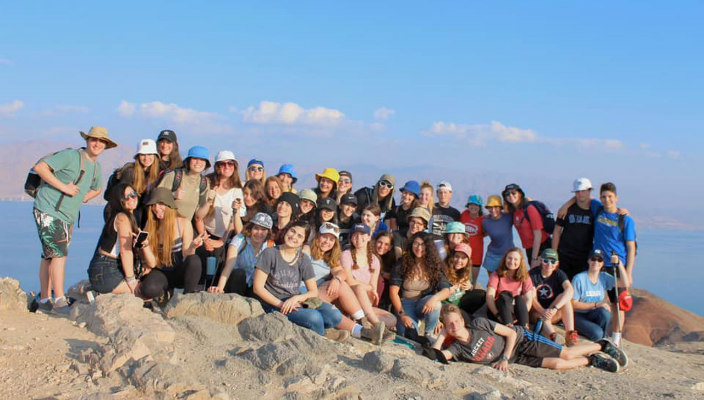 Group of smiling URJ Heller High students standing on a sandy hill in Israel