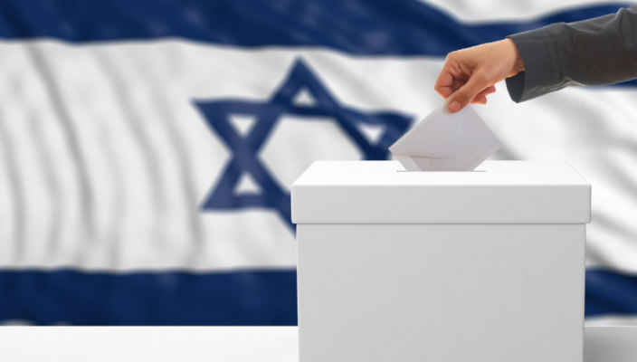 Hand dropping a ballot into a ballot box in front of the Israel flag