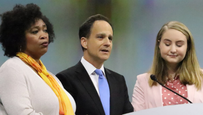 Rabbi Jonah Pesner standing at a podium addressing the URJ Biennial with two other speakers on each side of him