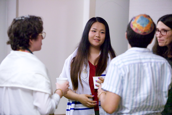 Diverse group of people wearing tallit and talking after Shabbat services