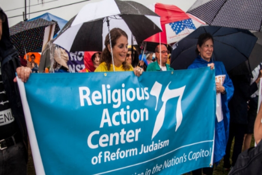 Activists marching in a rally and holding a Religious Action Center banner
