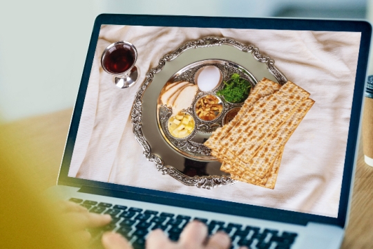 Hands on a keyboard with a seder plate on the computer screen