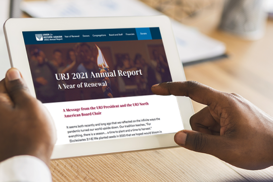 Hands holding a tablet device with the URJ 2021 Annual Report on the screen