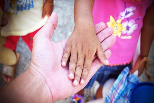 Childrens hands touching one adult hand 