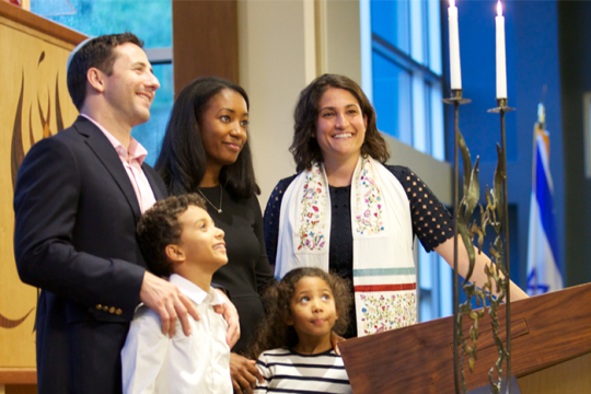 Family and cantor lighting candles in a synagogue