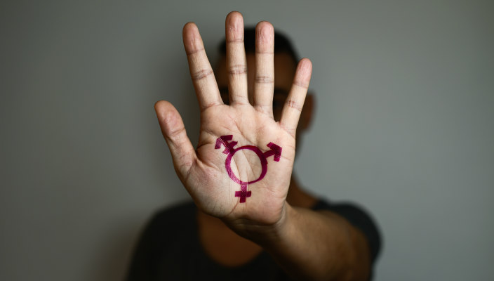 Transgender symbol in magenta ink painted on an outstretched palm obstructing the person's face