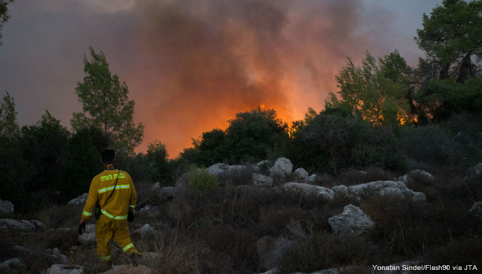 An Israeli firefighter watches a blaze from afar