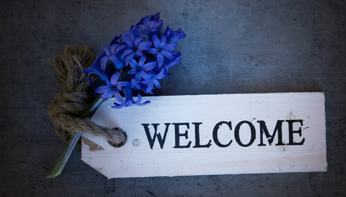Welcome written on a wooden sign with flowers